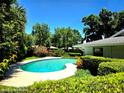 Serene kidney-shaped pool surrounded by lush greenery, creating a private and tranquil backyard oasis at 5096 The Oaks Cir, Orlando, FL 32809