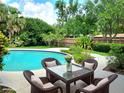 Inviting outdoor seating area next to a sparkling pool, perfect for relaxation and entertaining in a private backyard setting at 5096 The Oaks Cir, Orlando, FL 32809