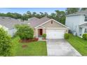 Aerial view of a beige single-Gathering home with a well-kept lawn and a driveway at 522 Anne St, Deland, FL 32724