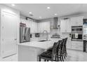 Well-appointed white kitchen featuring stainless steel appliances, quartz countertops and an island with breakfast bar at 7454 Gathering Dr, Reunion, FL 34747