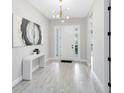 Bright foyer with gray walls, gray floors, console table with decor, and a striking light fixture highlighting the airy space at 977 Talon Pl, Winter Springs, FL 32708