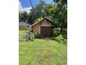 Detached garage with wood doors surrounded by lush greenery and a white picket fence at 1307 Mabbette St, Kissimmee, FL 34741