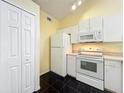Compact kitchen features white appliances, cabinets, black tile flooring, and ample storage space at 1751 Chatham Cir, Apopka, FL 32703