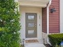 Close-up of a modern front door with glass panels, stylish lighting, and manicured landscaping at 193 E Warren Ave, Longwood, FL 32750