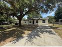 Inviting home with a spacious driveway, lush yard, and mature trees, offering curb appeal and outdoor space at 212 Dorothy St, Auburndale, FL 33823