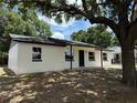 A bright white house with black accents and a dark roof stands on a lush lawn beneath the shade of a tree at 212 Dorothy St, Auburndale, FL 33823