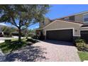 Attractive townhouse featuring a paved driveway and mature tree in the front yard at 2183 Leather Fern Dr, Ocoee, FL 34761