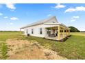 Exterior view of a white farmhouse with a metal roof and wrap-around porch at 22212 Sw 210Th Ave, Dunnellon, FL 34431