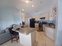 Functional kitchen with granite countertops, white cabinetry, and modern black appliances at 8509 Sw 136Th Loop, Ocala, FL 34473