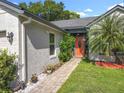 Close-up of the home's entrance, showcasing the orange front door, stone pathway, and mature landscaping at 1044 Dees Dr, Oviedo, FL 32765