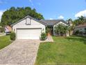 A well-maintained single-story home featuring a brick driveway and lush green lawn at 1044 Dees Dr, Oviedo, FL 32765