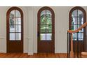 Light and airy entryway features striking brown arched doors, sidelights, and wood floors at 1394 Grove Ter, Winter Park, FL 32789