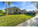 Inviting home exterior featuring a well-manicured lawn, mature trees, and charming architectural details at 1956 Southern Dunes Blvd, Haines City, FL 33844