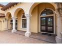 Exterior detail of arched columns, decorative pillars, and a glass-paneled front door with 'hello' welcome mat at 5413 Via Veneto Ct, Sanford, FL 32771