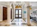 Elegant foyer featuring tile floors, decorative columns, arched doorways, and a stylish light fixture at 5413 Via Veneto Ct, Sanford, FL 32771