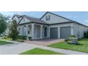 Inviting home showcasing a manicured lawn and gray exterior, complete with a two-car garage and covered porch at 9863 Summerlake Groves St, Winter Garden, FL 34787