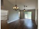 Inviting living room featuring wood-look floors, large windows, a modern ceiling fan and decorative chandelier at 9923 Dean Acre Dr, Orlando, FL 32825