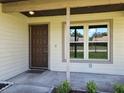 A cozy front porch area with a beige door and large window, and green shrubs at 10018 Chesham Dr, Orlando, FL 32817