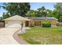Inviting single-story home with stone details, a two-car garage, and a curved brick-lined walkway at 12 Horseman Cv, Longwood, FL 32750
