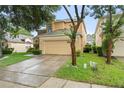 Beige two-story home featuring a well-kept lawn, mature trees, and a two-car garage at 1400 Holly Glen Run, Apopka, FL 32703