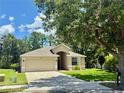Traditional house with manicured lawn, mature trees, and attached two-car garage at 14715 Buckingham Gate Ct, Orlando, FL 32828