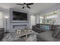 Cozy living room featuring a gray sectional sofa, custom fireplace, and plenty of natural light at 1811 Caribbean View Ter, Kissimmee, FL 34747