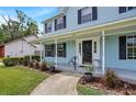 Inviting front porch with white columns, dark shutters, and manicured landscaping at 201 Garden Ln, Longwood, FL 32750