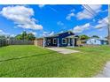 Blue house with a large lawn, carport, and wooden fence on a sunny day at 205 9Th St, St Cloud, FL 34769
