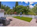 Spacious backyard with a paver patio, playset on artificial grass, and white vinyl fencing at 2604 Marble Ave, Orlando, FL 32803