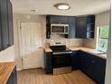 Well-lit kitchen featuring wood countertops, navy cabinets, and stainless steel appliances at 3629 Main St, Sanford, FL 32771