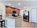 A kitchen features wooden cabinets, granite countertops, stainless steel refrigerator, and laminate flooring at 533 Mount Olympus Blvd, New Smyrna Beach, FL 32168