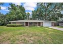 Charming one-story home features a spacious lawn, two-car garage, and red front door at 5460 Se 28Th St, Ocala, FL 34480
