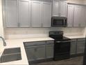 Well-lit kitchen with gray cabinets, modern appliances, white countertops, and a stainless steel sink at 12337 Turtle Grass Dr, Orlando, FL 32824