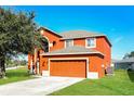 Two-story home featuring a two-car garage, an arched window, and a well-maintained lawn at 148 Conch Dr, Kissimmee, FL 34759