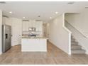 Open-concept living room flows into a kitchen with stainless steel appliances and center island at 16390 Bird Of Paradise Ave, Clermont, FL 34714