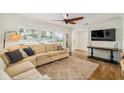 Cozy living room features wood floors, neutral sectional sofa, large windows with plantation shutters, and a ceiling fan at 2114 Geigel Ct, Orlando, FL 32806