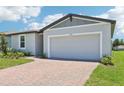 A beautiful house with a two-car garage and a brick driveway is landscaped with green shrubs and grass at 2365 White Tail St, Davenport, FL 33837