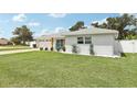 Landscaped single-story home featuring a manicured lawn, white fencing, and mature trees at 2926 Carriage Dr, South Daytona, FL 32119