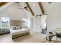 Bright main bedroom featuring a vaulted ceiling with wood beams, a ceiling fan, a tufted headboard, and light wood floors at 4343 Juliana Lake Dr, Auburndale, FL 33823