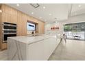 Modern kitchen with stainless steel appliances, oversized waterfall island, and views of outdoor pool at 4934 Legacy Oaks Dr, Orlando, FL 32839