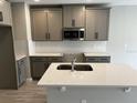 Modern kitchen featuring gray cabinets, stainless steel microwave, subway tile backsplash, and an island with a sink at 5101 Prairie Preserve Run, St Cloud, FL 34772