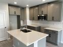 Modern kitchen with gray cabinets, stainless steel microwave, subway tile backsplash, and a large island with a sink at 5101 Prairie Preserve Run, St Cloud, FL 34772