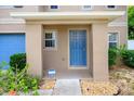Covered front porch with a blue front door and decorative landscaping at 1033 Sabine Pl, Kissimmee, FL 34759