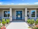 Welcoming front porch with stone columns, manicured lawn, and a blue front door at 14243 County Road 450, Umatilla, FL 32784