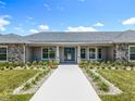 Inviting front entrance with stone accents, manicured lawn, and a long walkway at 14243 County Road 450, Umatilla, FL 32784