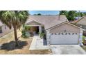 Charming single-story home featuring a two-car garage, covered porch, and lush landscaping at 1614 Oak Hill Trl, Kissimmee, FL 34747