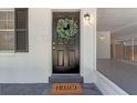 Close-up of a stylish black front door with a decorative wreath and 'HELLO' door mat at 235 Ruth Blvd, Longwood, FL 32750