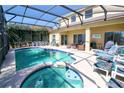Beautiful screened-in pool and spa surrounded by seating and lush landscaping at 331 Bridgewater Dr, Davenport, FL 33897