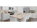 Modern kitchen with stainless steel appliances, white cabinetry, stone countertops and stylish fixtures at 5202 Orchard Oriole Loop, Bartow, FL 33830