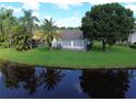 Backyard view of a lush lawn, mature trees, and serene lake, perfect for relaxation at 5804 Plum Pudding Ct, Orlando, FL 32821